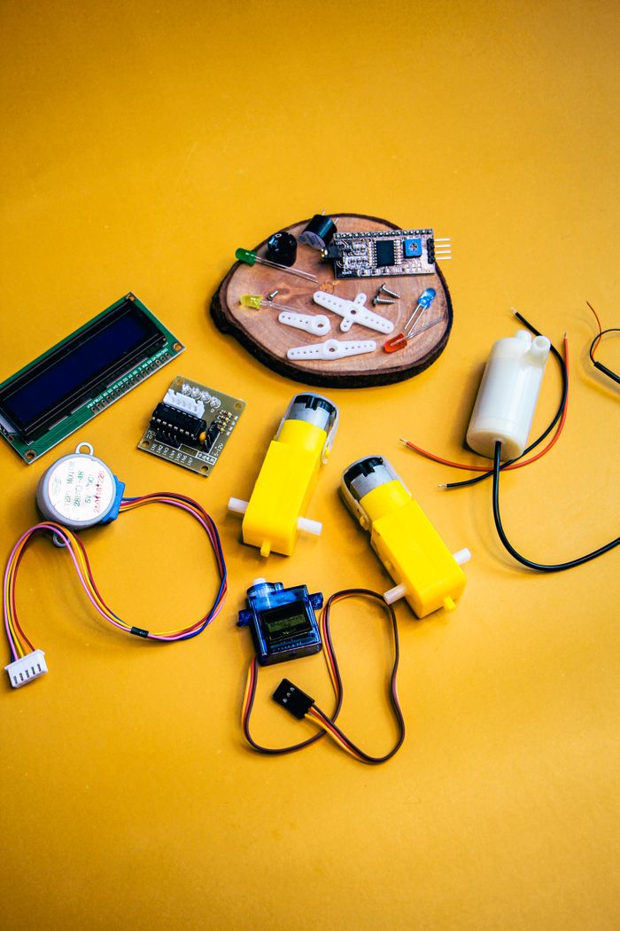services-04 Top view of robotic kit parts on vibrant yellow background, ideal for tech projects.