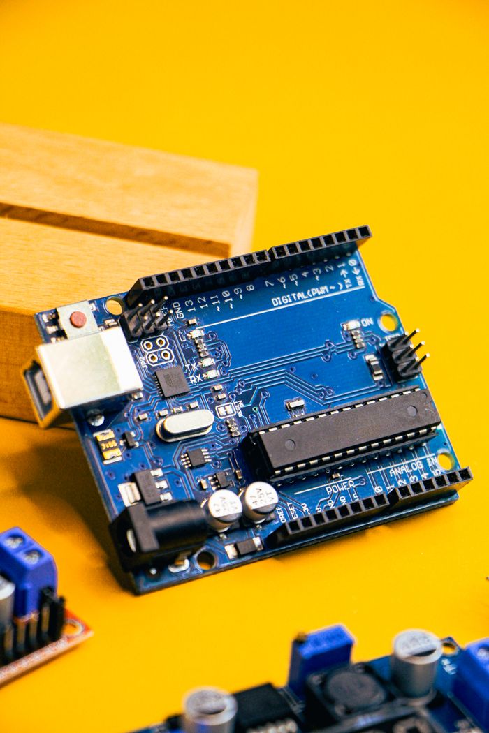 services-02 Close-up of an Arduino microcontroller on a vibrant yellow background, showcasing electronic innovation.
